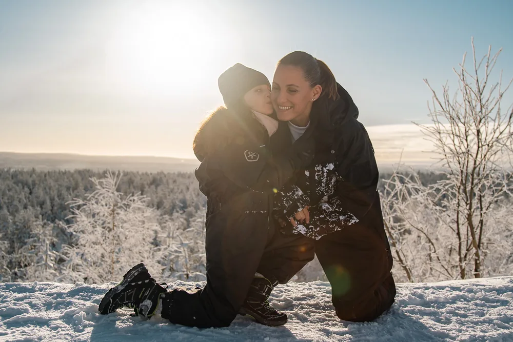 Two figures backlit in a snowy forest at low sun