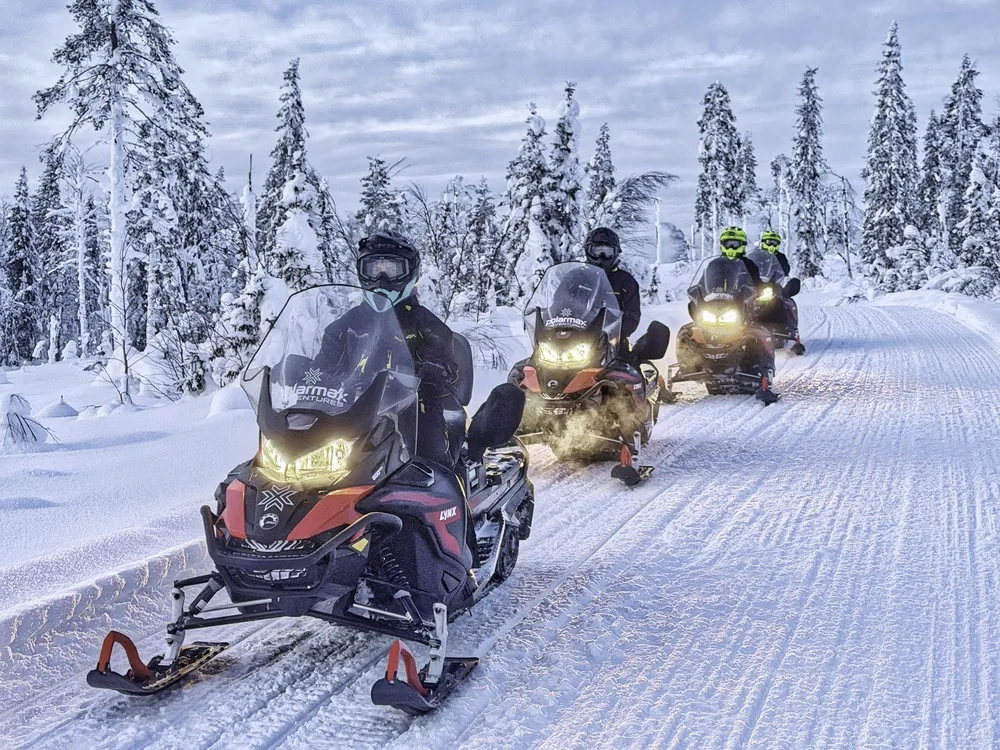 Snowmobilers riding a groomed forest trail
