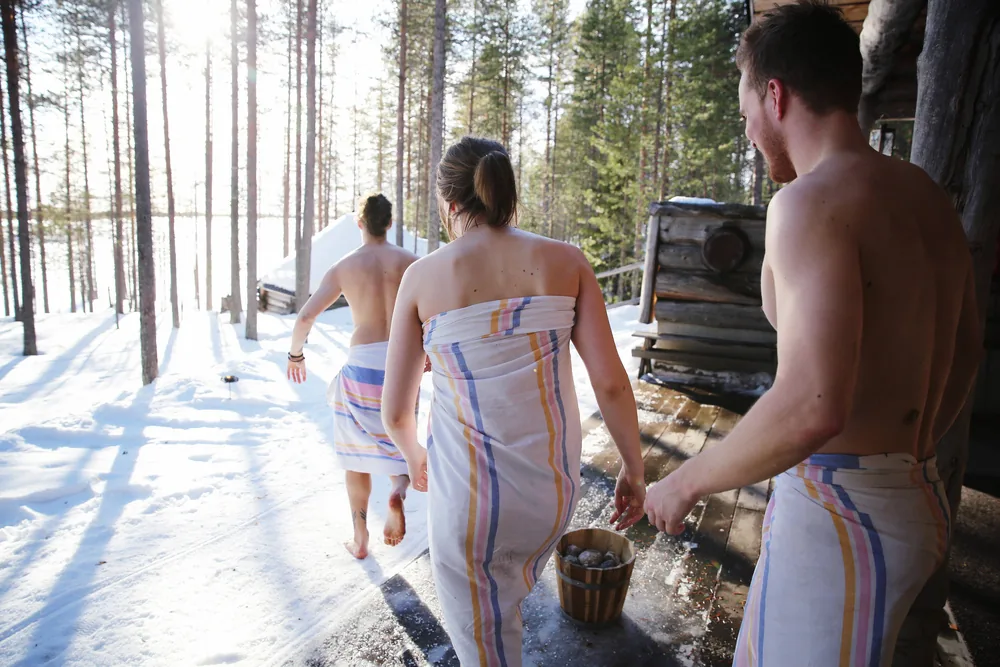 Sauna guests cooling outside a tent sauna in winter