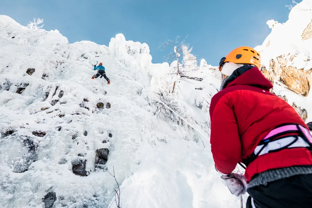 An ice climber ascending a frozen rock face