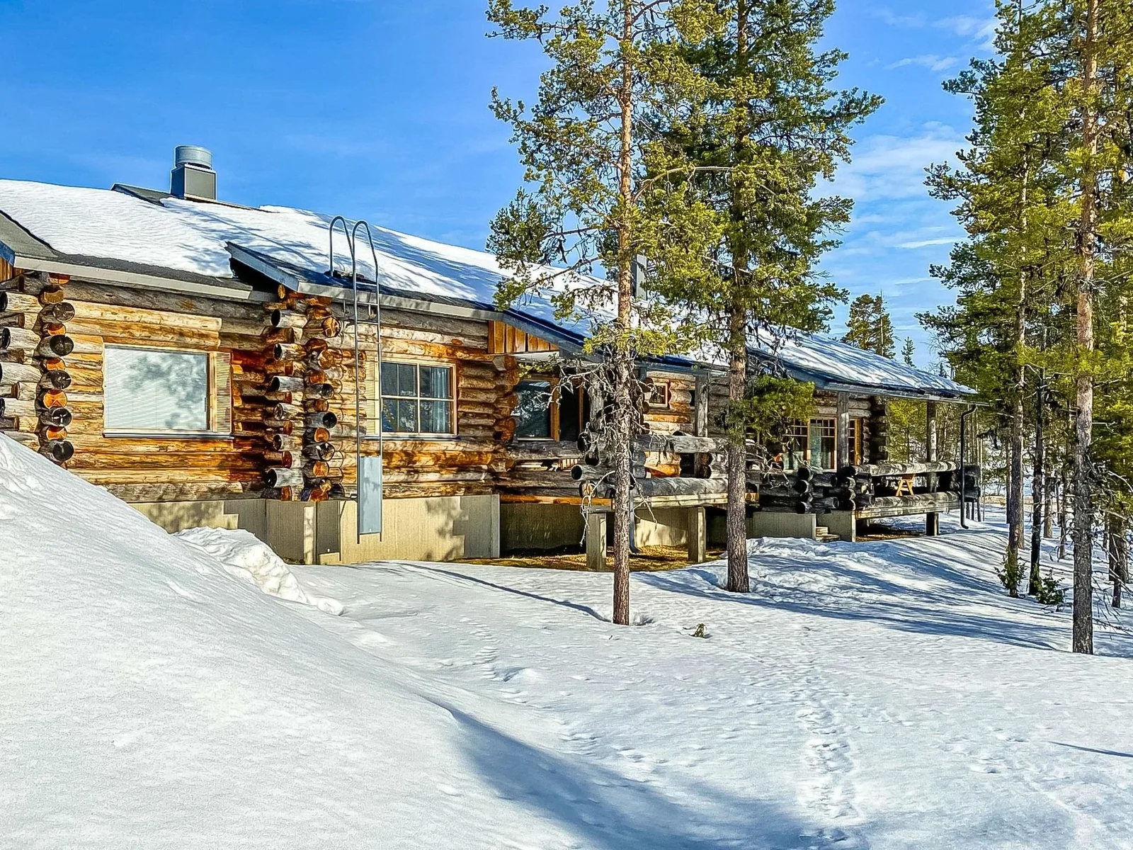 Kairapolanne B, a log chalet banked in deep snow between pines