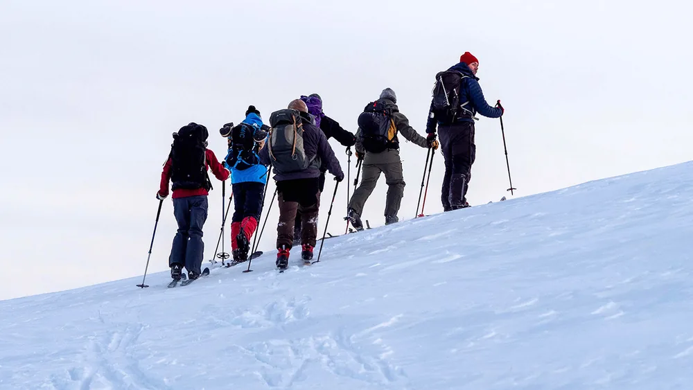 A group of ski tourers crossing a snow slope in single file