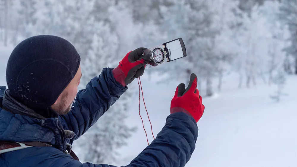 A person checking field equipment in a frost-laden forest